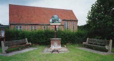 The Rackheath village sign. One memorial plaque commemorating the 467th Bomb Group is at the base of the sign, another is on the left-hand bench.